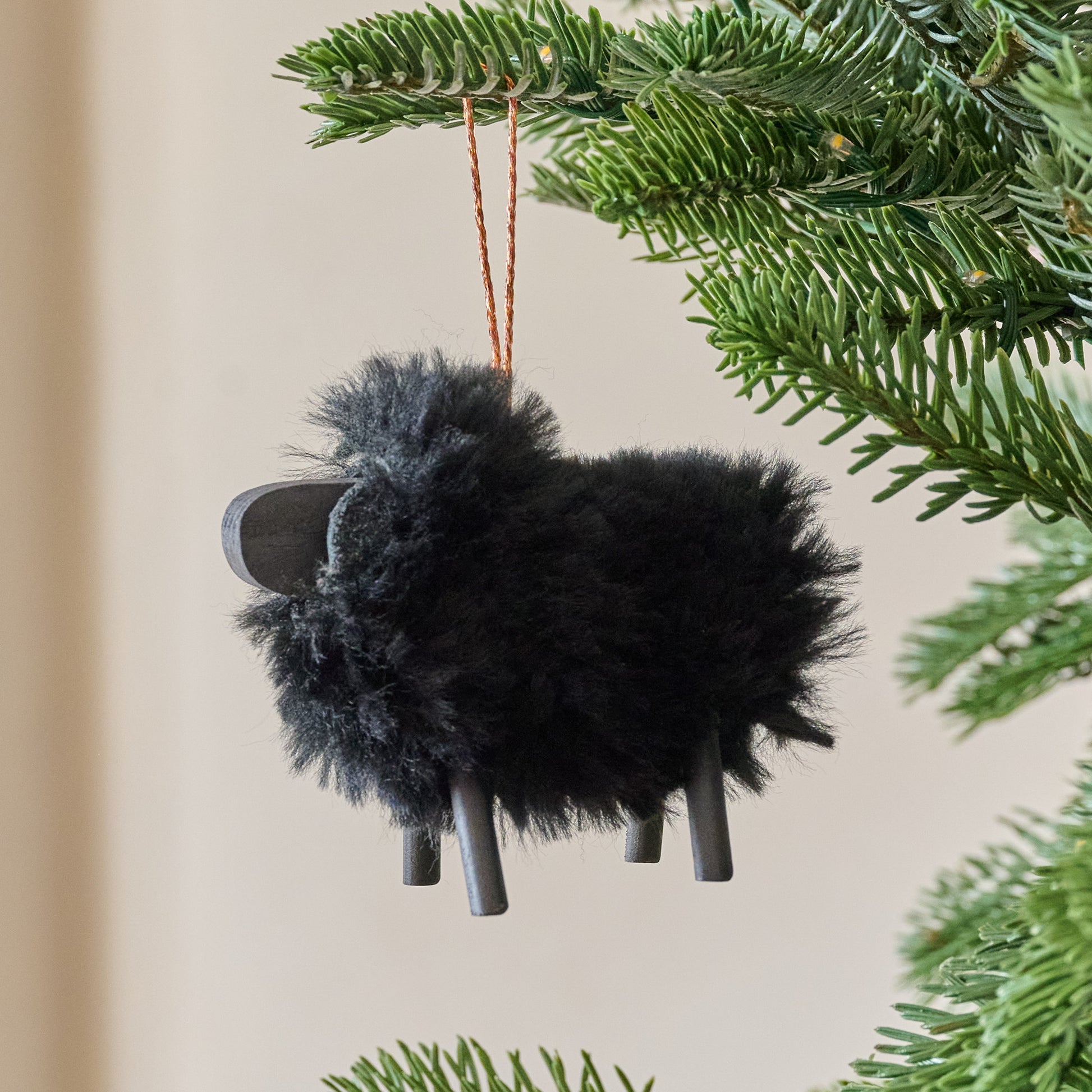 Black Handcrafted Shearling Sheep Ornament shown hung from tree