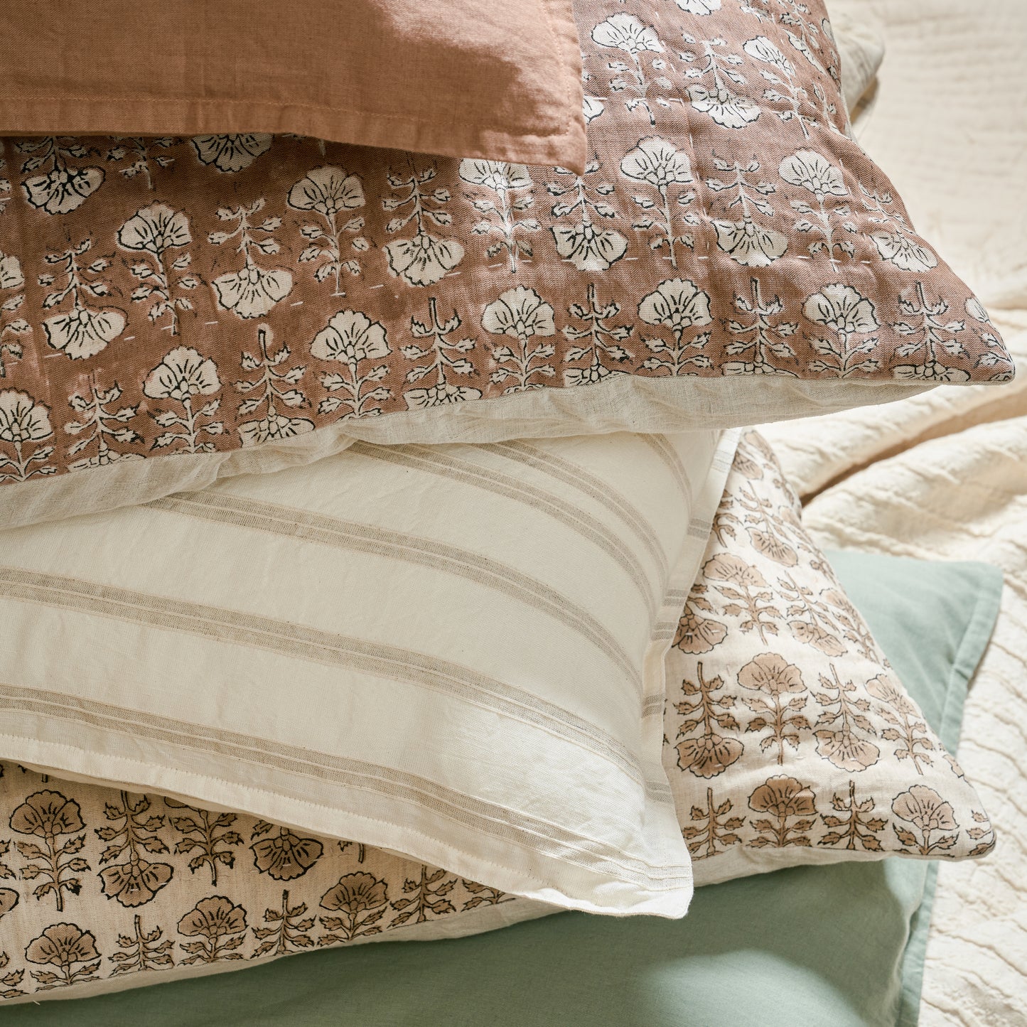 Flora Natural Printed Pillow in a stack of pillows