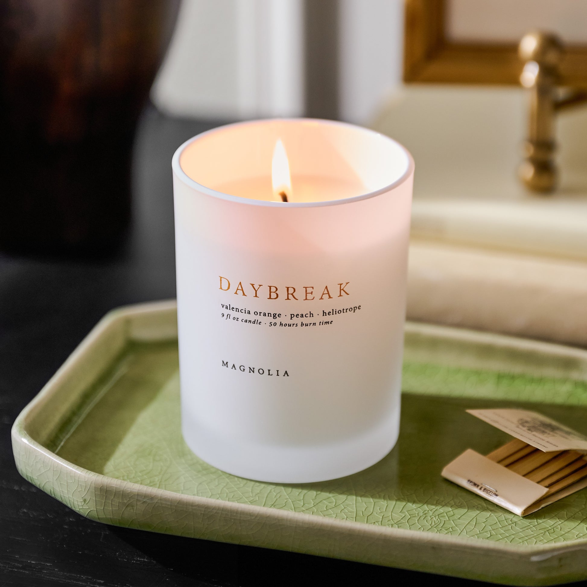 Magnolia Daybreak Candle on a green ceramic tray with match book
