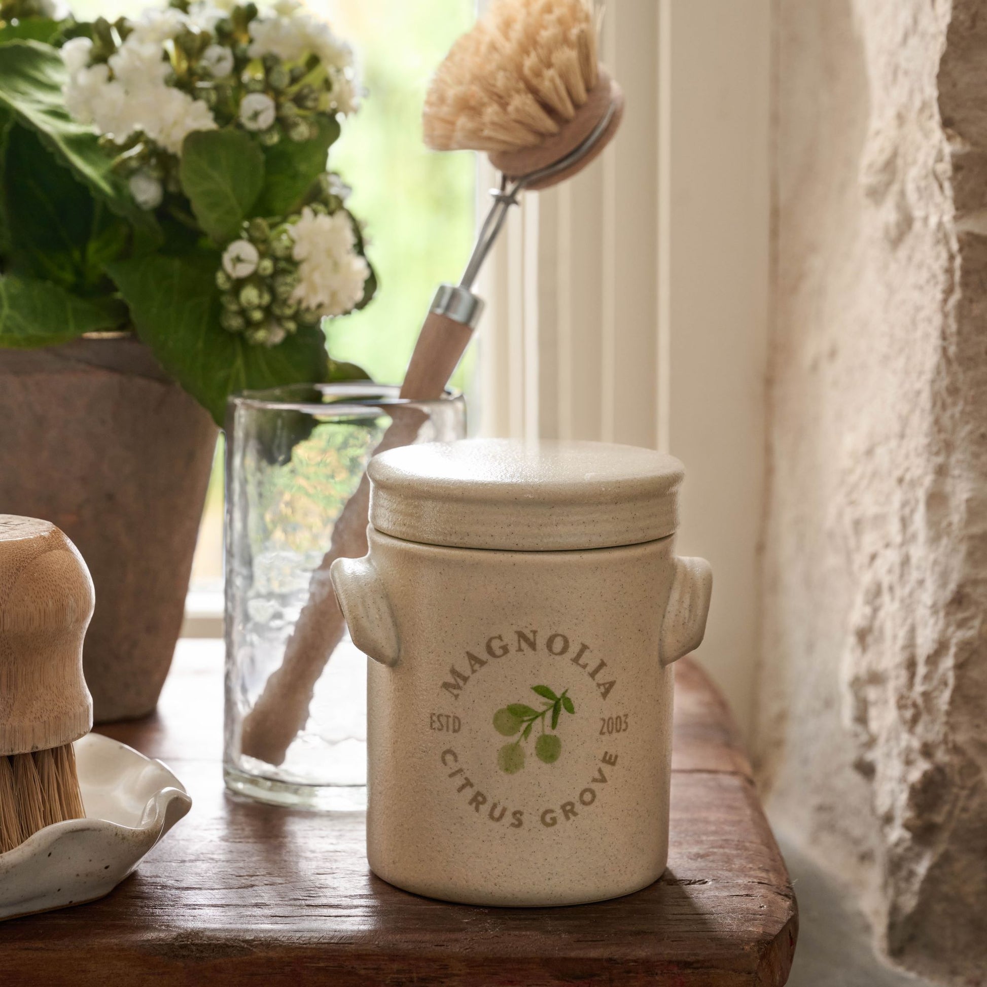 Magnolia Citrus Grove Candle with lid on wooden riser