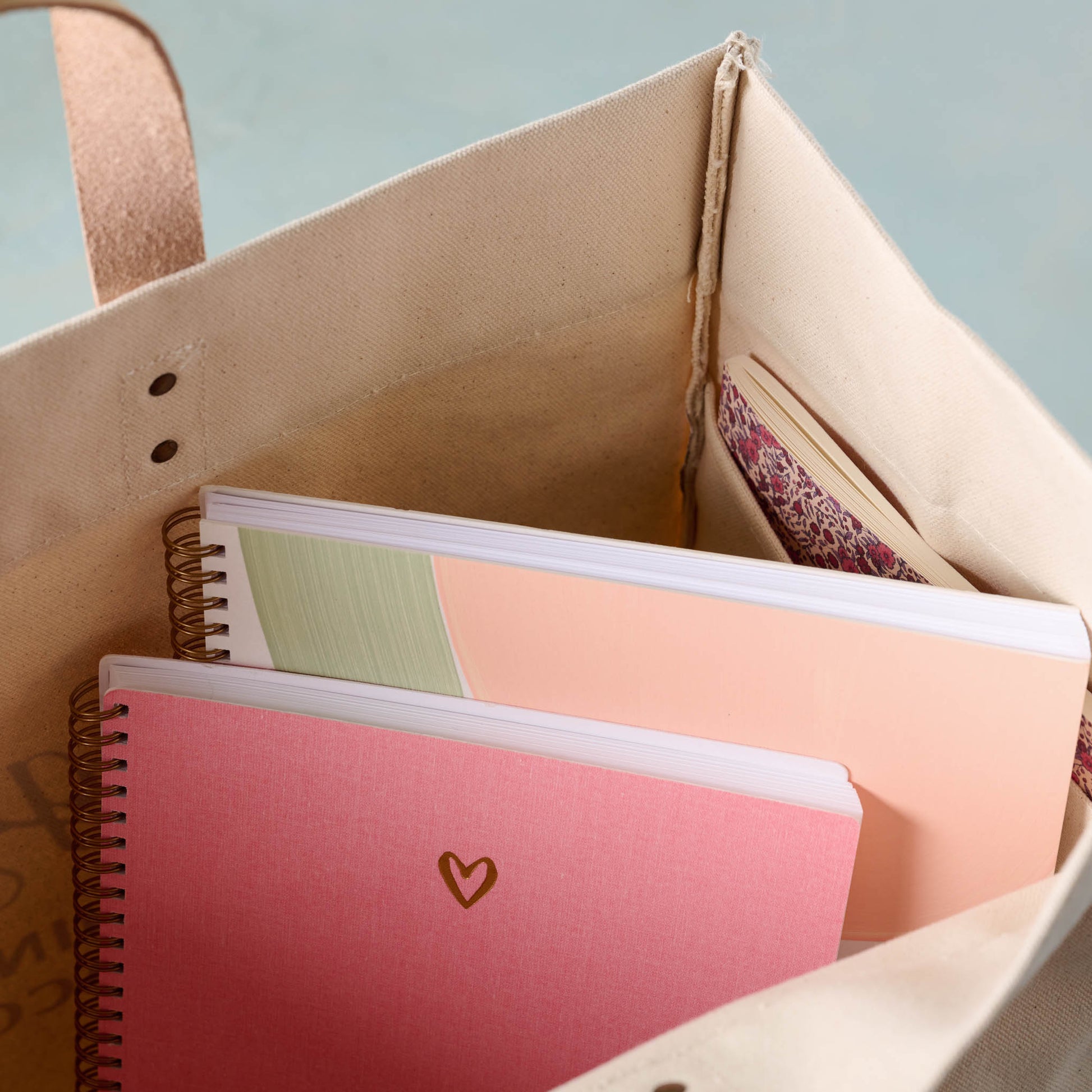 close up of Magnolia Cora Script Large Canvas Tote containing pink heart notebook and melon sketchbook