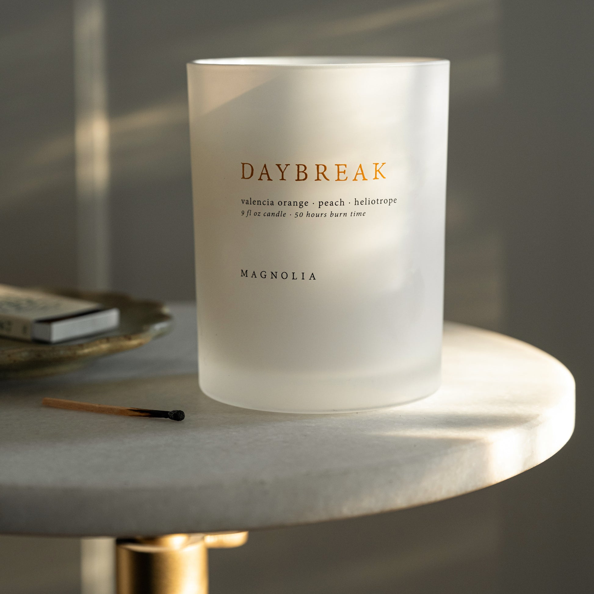 Magnolia Daybreak Candle on a side table