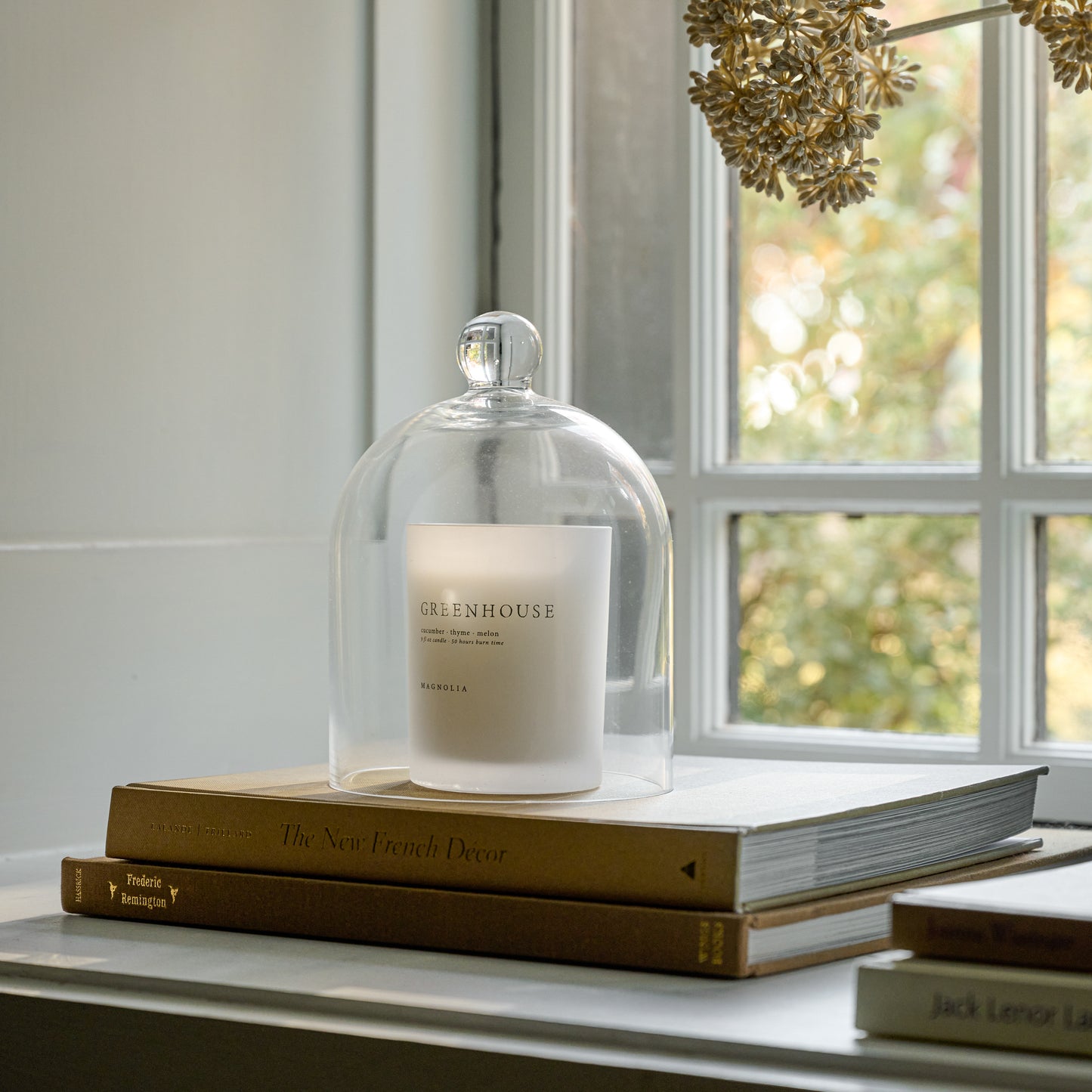 Magnolia Greenhouse Candle on books in window sill