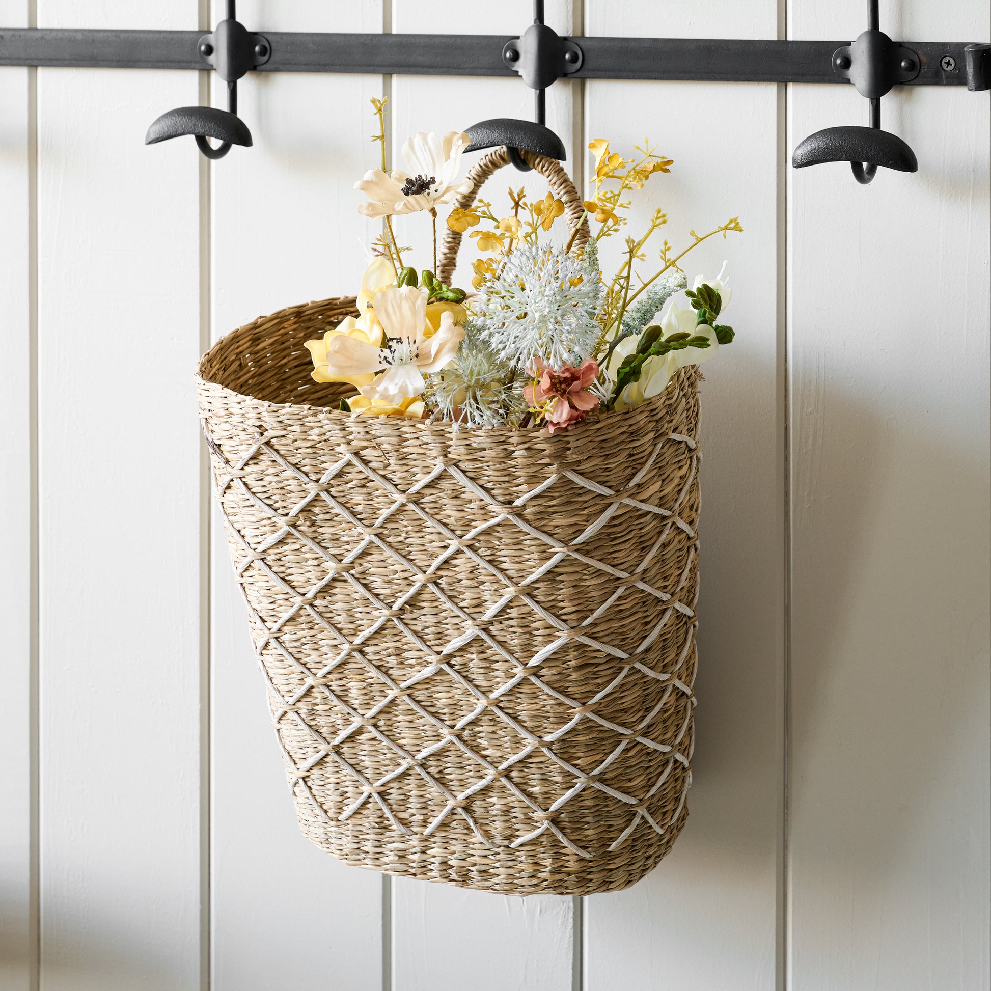 Close up of wicker basket with florals hanging from long duke metal wall hook