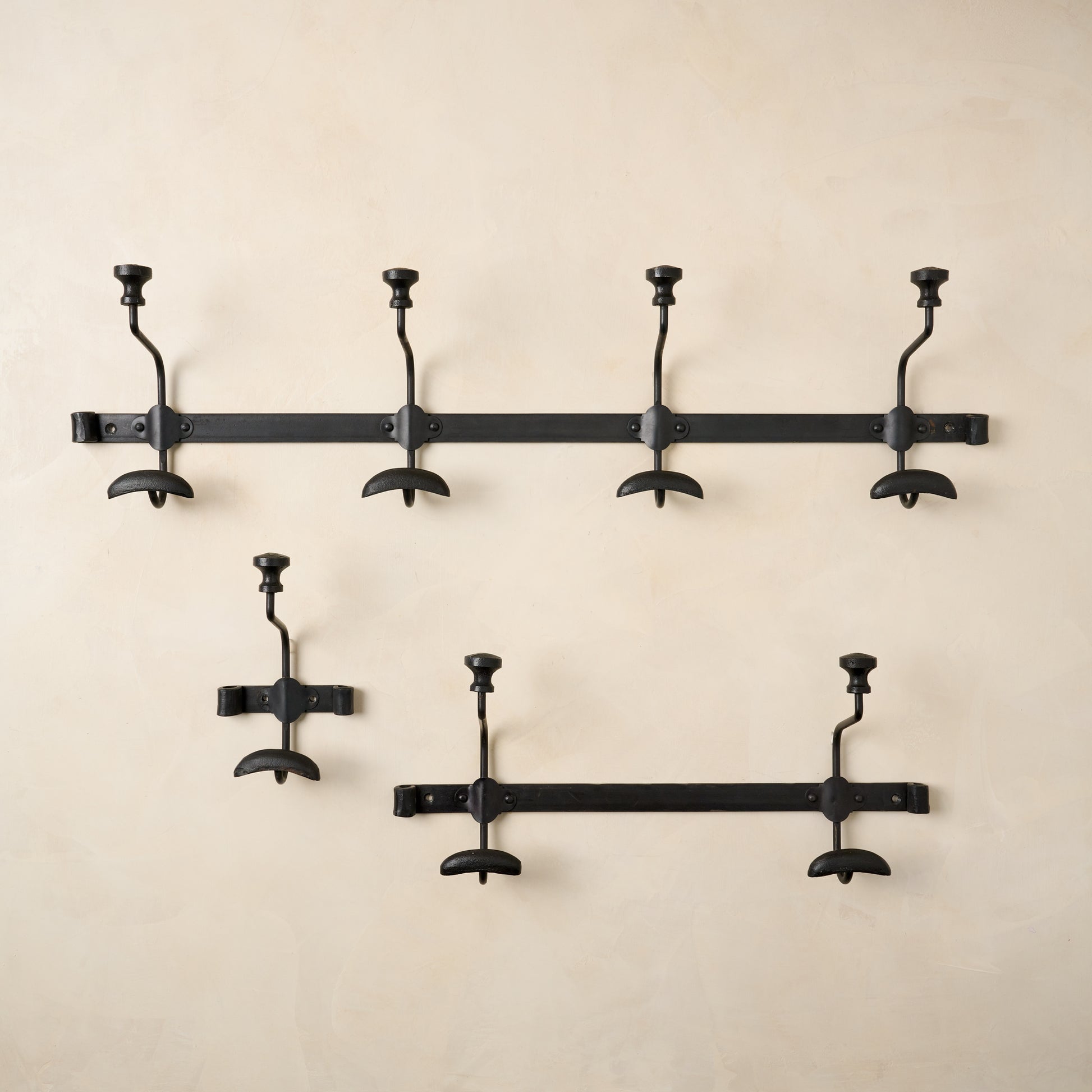 Three sizes of Duke metal wall hooks pictured on a wall.