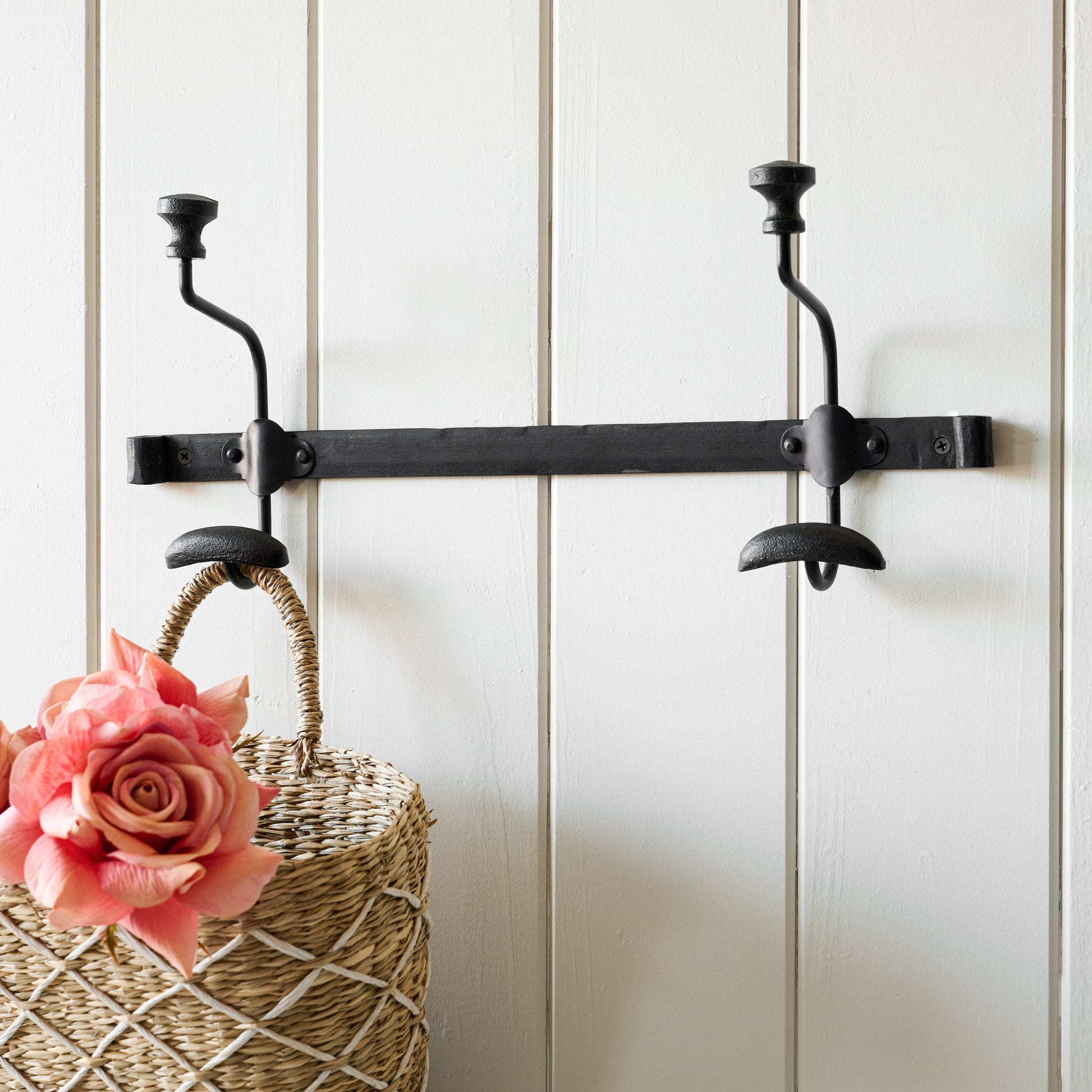 Short duke metal wall hook with wicker basket hanging from one hook.