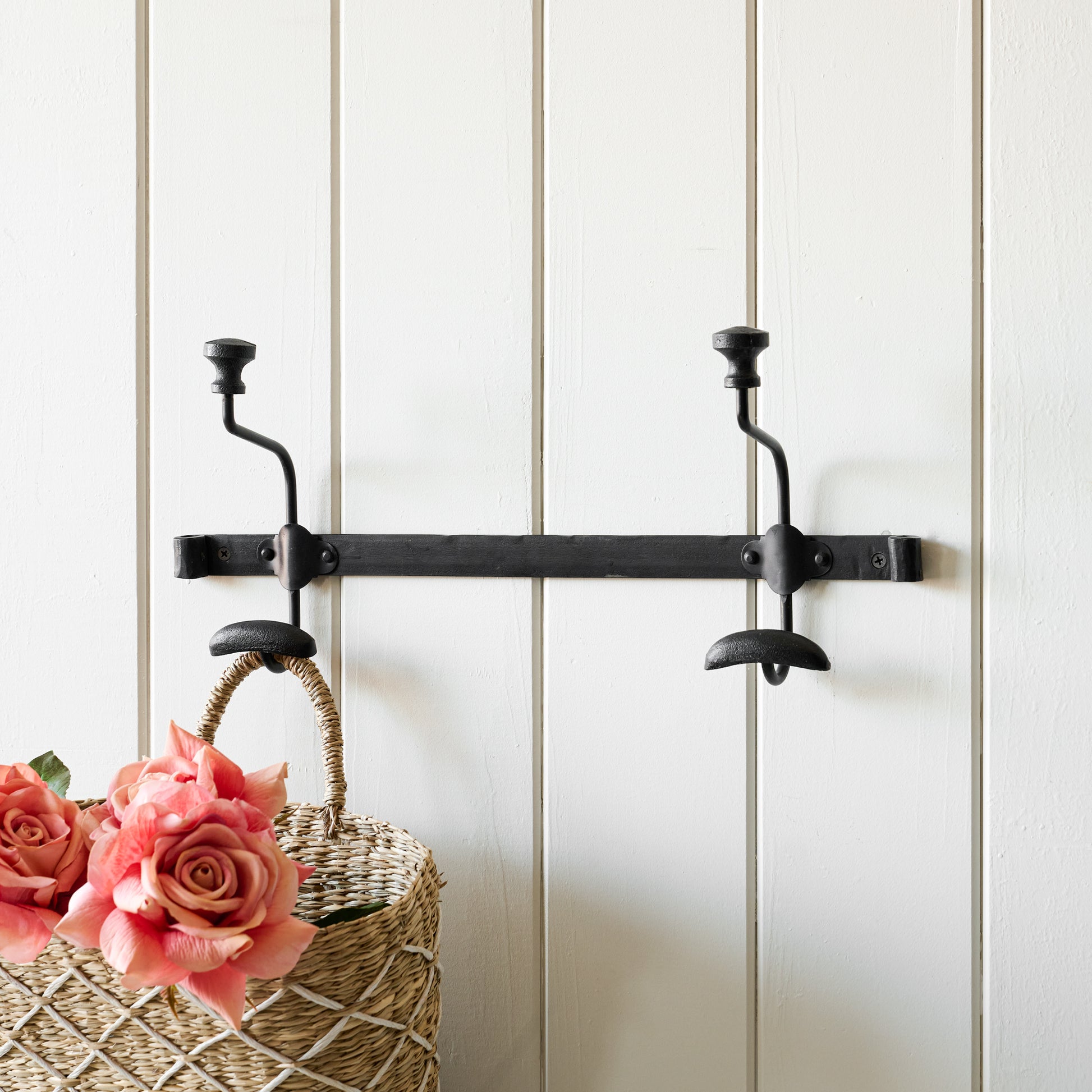 Different angle of short duke metal wall hooks with wicker basket hanging from one hook.