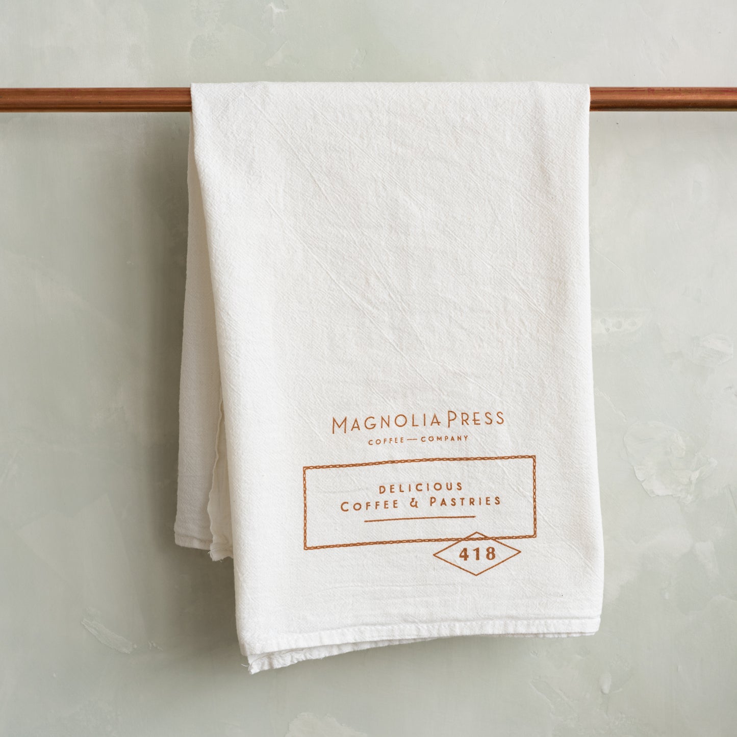 white tea towel with magnolia press logo in copper