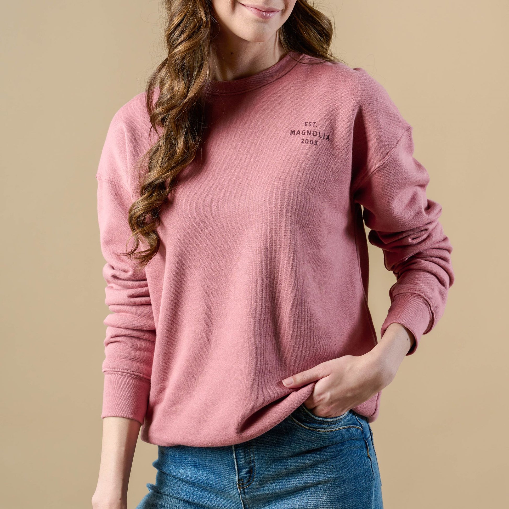 Sweatshirt in mauve color on model. Small text on front of sweatshirt, upper left chest reads Est. Magnolia 2003. Text color is maroon.