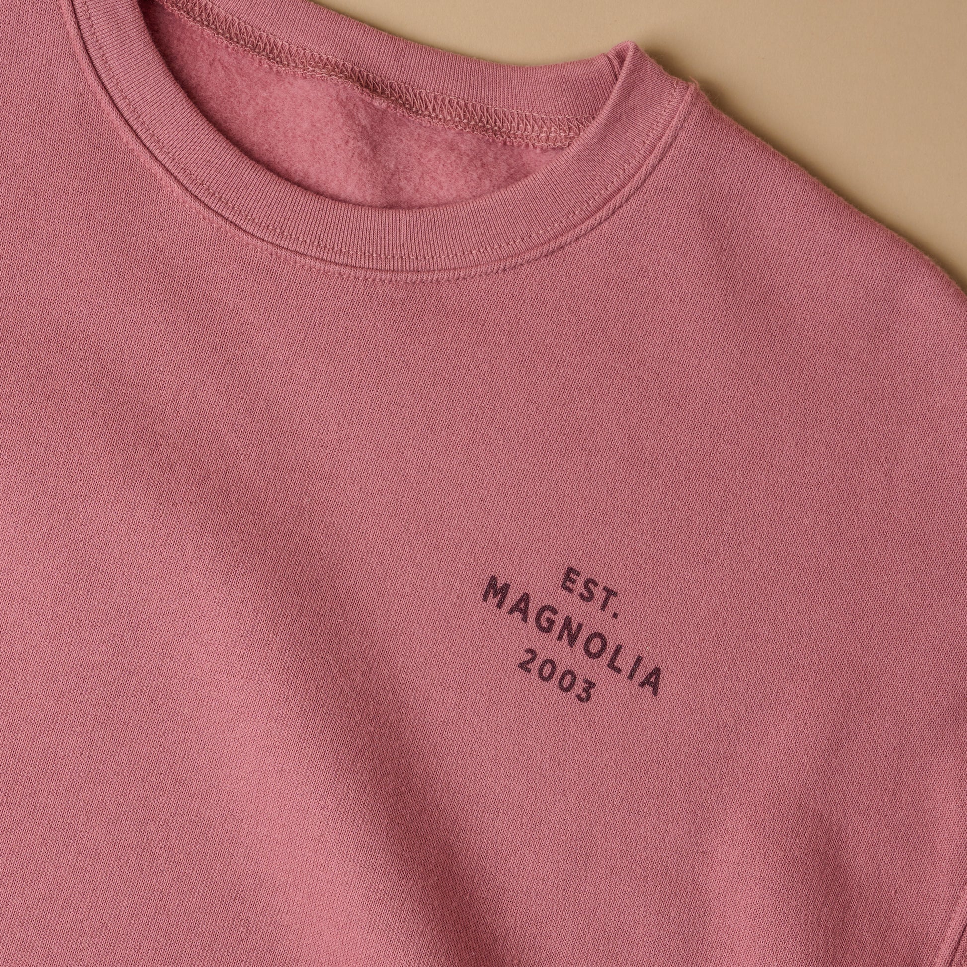 Close up of text on left chest. Reads EST. Magnolia 2003 in plain font, all capital letters.