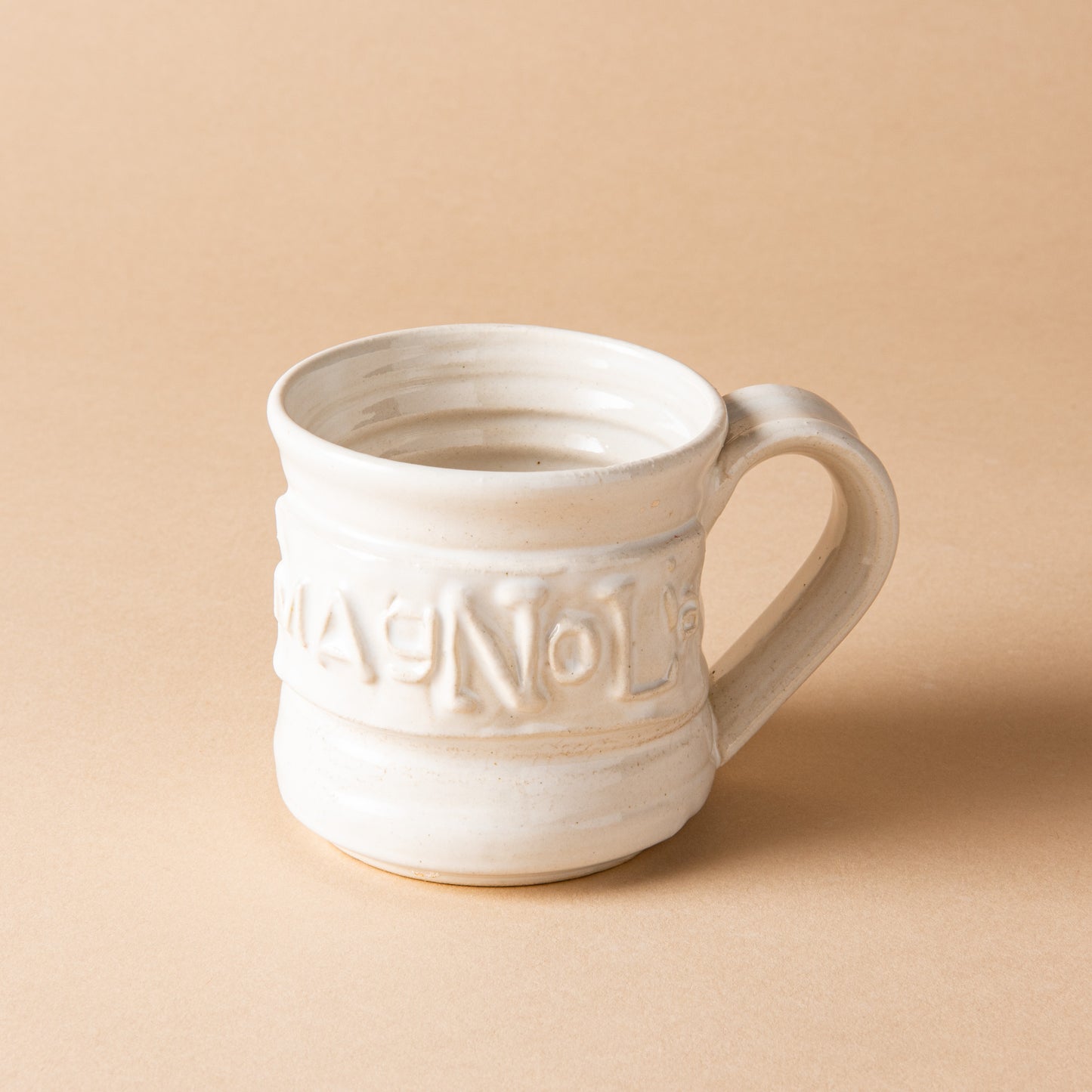 white handthrown ceramic mug with original Magnolia logo embossed on side