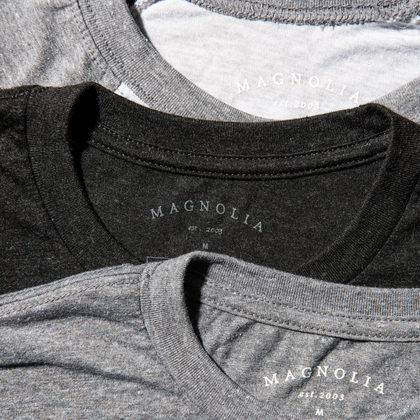 black heathered t-shirt with white magnolia silos seal logo