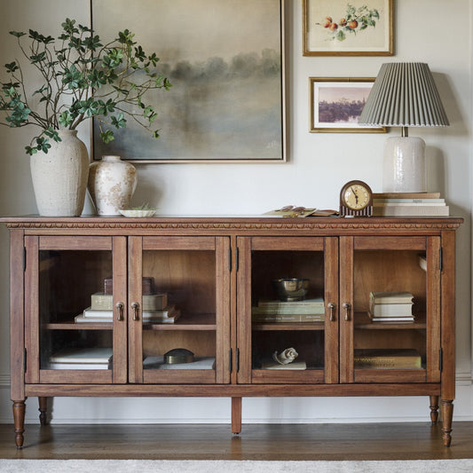 light wood sideboard with vases, stems and a lamp on the top.