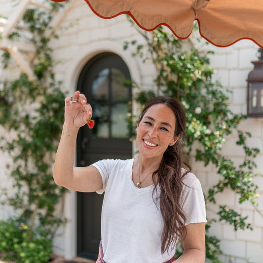Joanna Gaines standing outside her rose shed holding a strawberry.