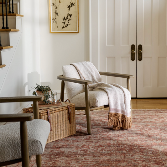 Two mid-century style chairs sit atop a large area rug, creating a warm, inviting atmosphere.