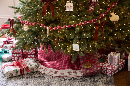 the bottom of a holiday tree showcasing beautifully wrapped holiday gifts with a festive holiday plaid tree skirt underneath.