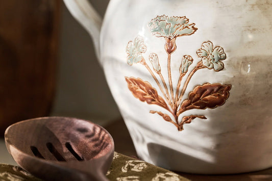 A close-up shot of the Elaine Floral Pitcher Crock and a slotted wooden spoon.