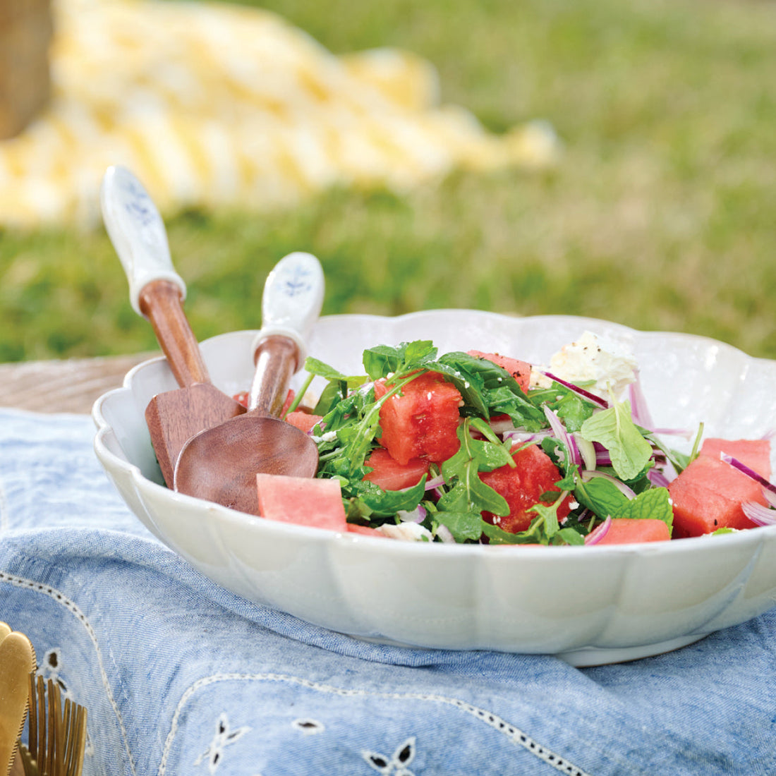 Watermelon & Feta Salad, ready to enjoy in a scalloped bowl with wooden tongs.