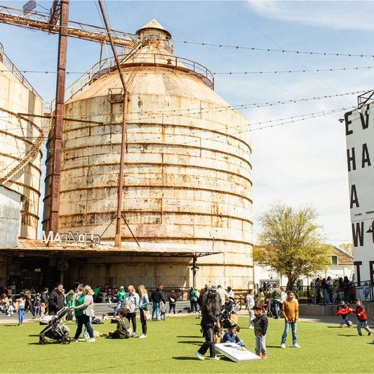 The Magnolia Silos stand in front of a green lawn surrounded by people in Waco, Texas.