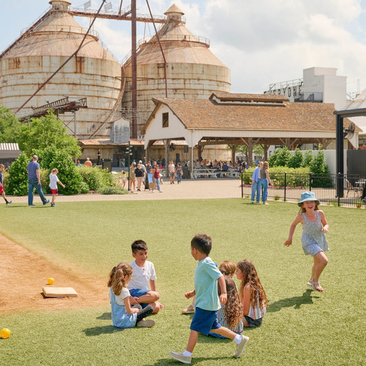Children running on a green lawn at the Magnolia Silos in Waco, Texas.