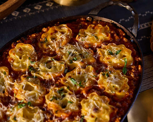A close-up shot of lasagna roll-ups fresh out of the oven, topped with homemade meat sauce, Parmesan cheese, and basil.
