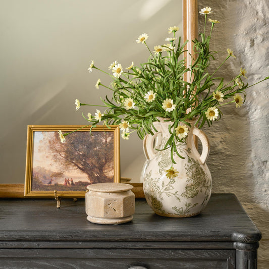 Wispy flowers sit in a distressed vase. 