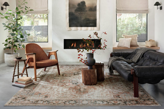 Living room with a couch, chair, fireplace, and printed rug.