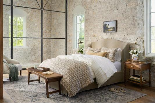 A bed is layered in Magnolia's Flora Block Print Quilt with matching shams and a neutral sheet set.
