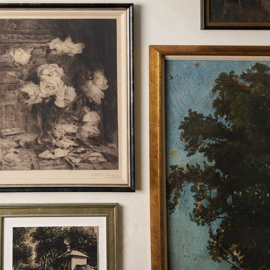 Gallery wall with a variety of framed pieces of art—including floral sketches and landscape paintings