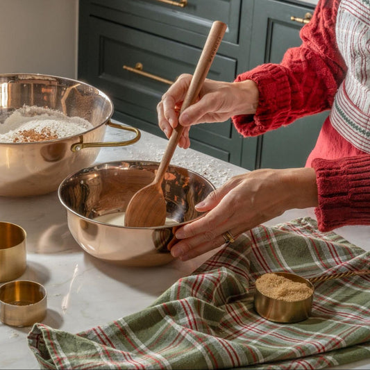 Person baking in the kitchen with copper bowls on a kitchen island.