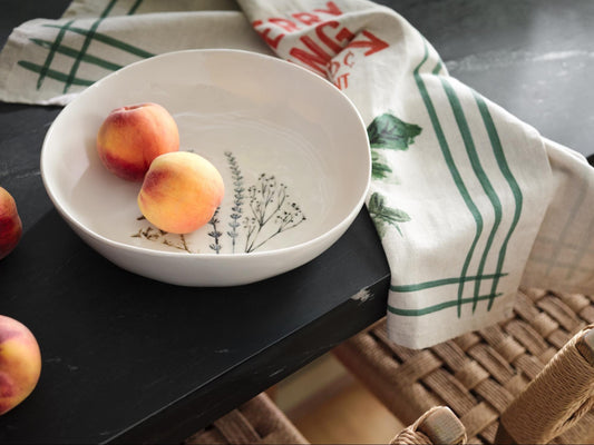 Bowl with whole peaches inside and a linen napkin.
