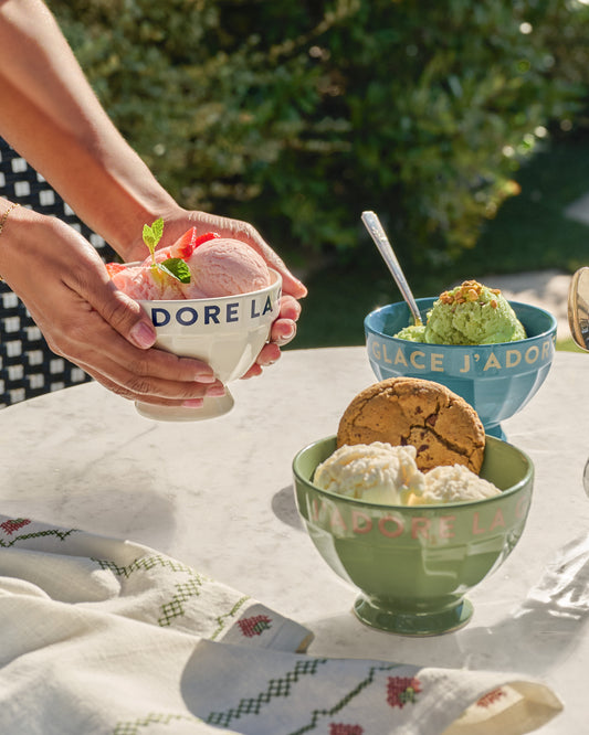 three bowls of ice cream with 'J'adore la glace" branding on a table outdoors.