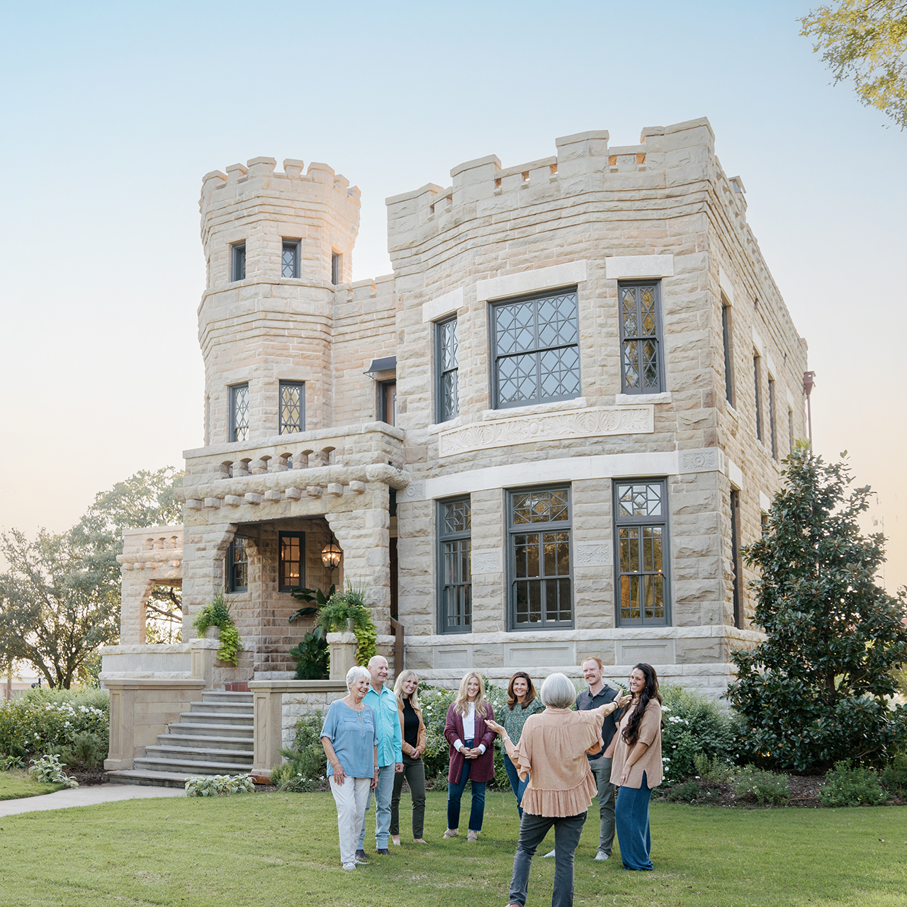 Group of people standing in front of a large stone castle-like building.
