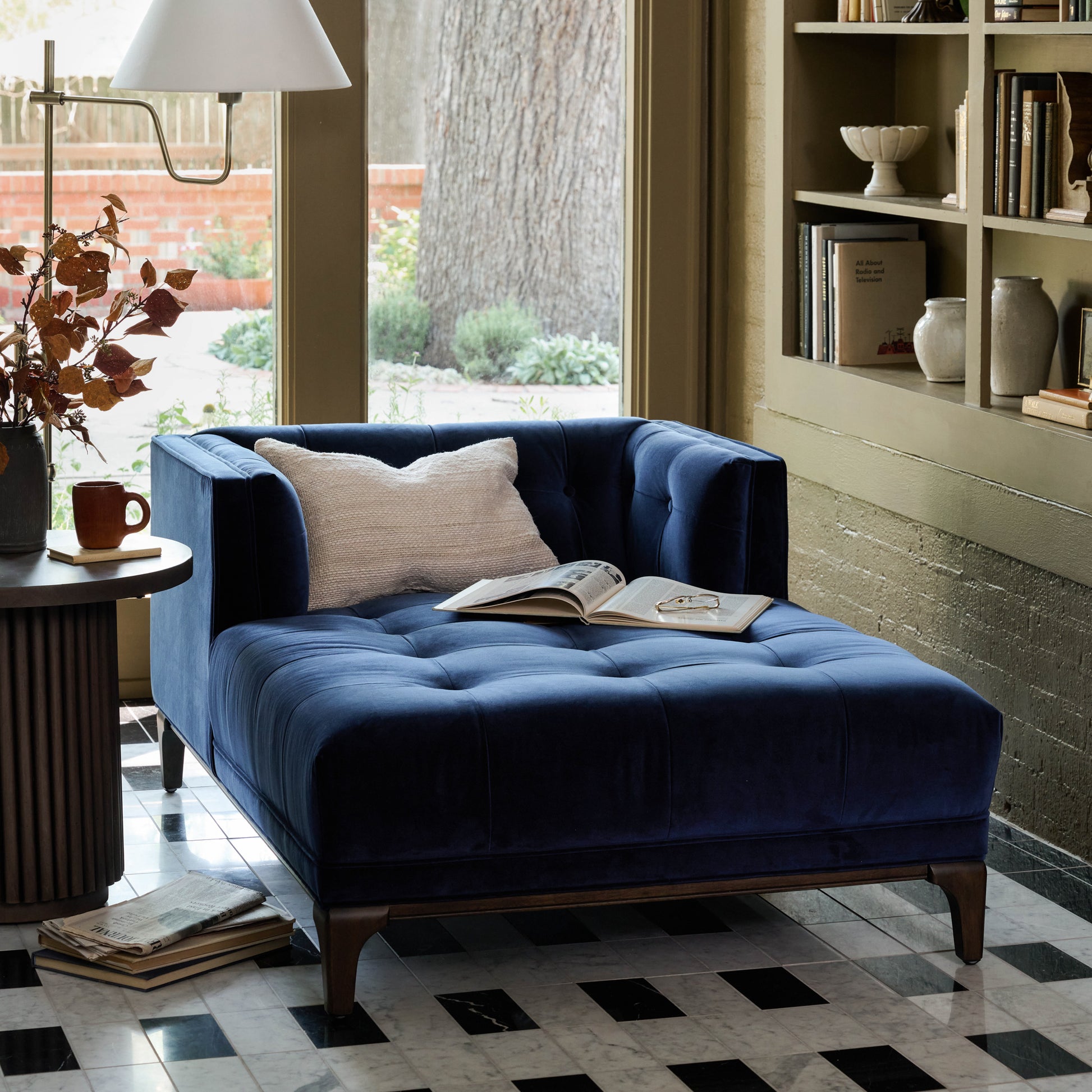 Elsie Chaise in midnight velvet in a sunroom with an open book on chaise