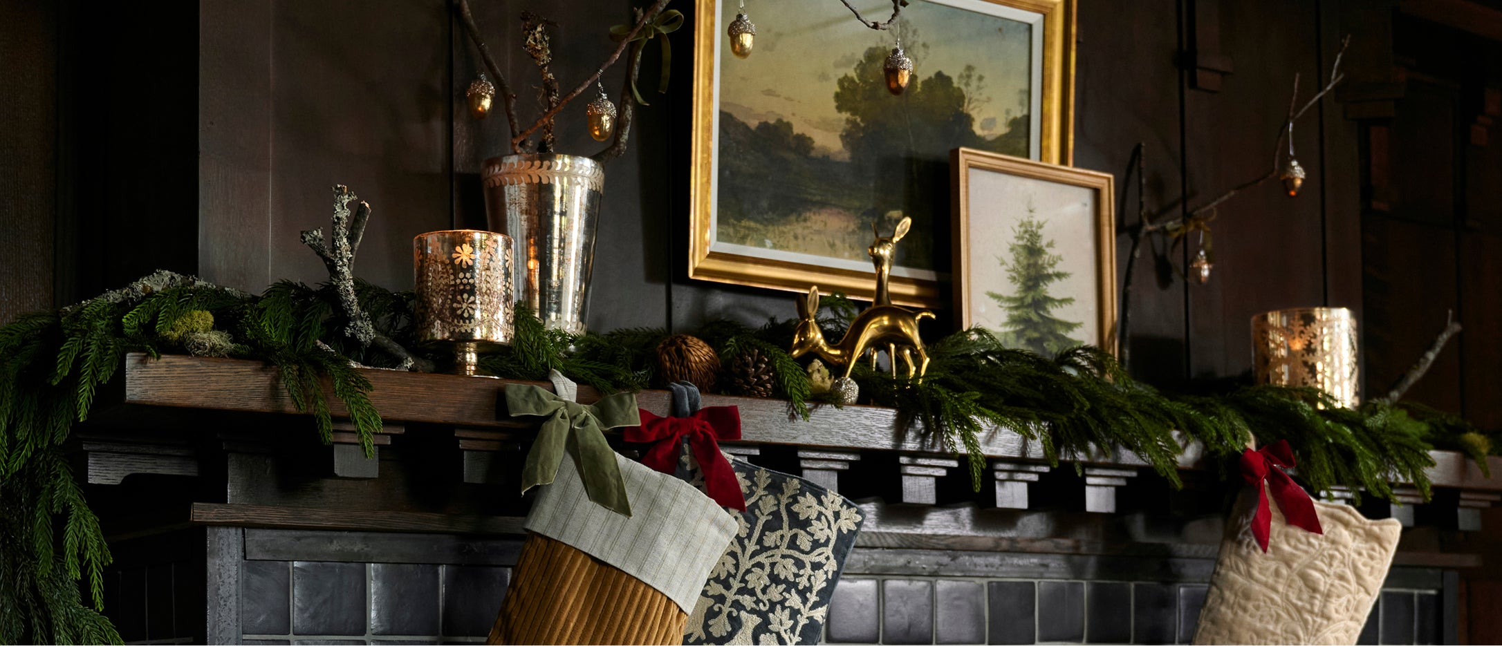 Decorative fireplace with stockings, candles, and framed pictures in a cozy room.