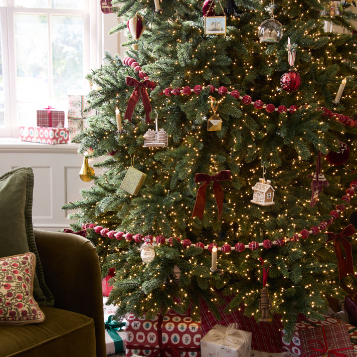 Decorated Christmas tree with lights and ornaments in a living room setting.