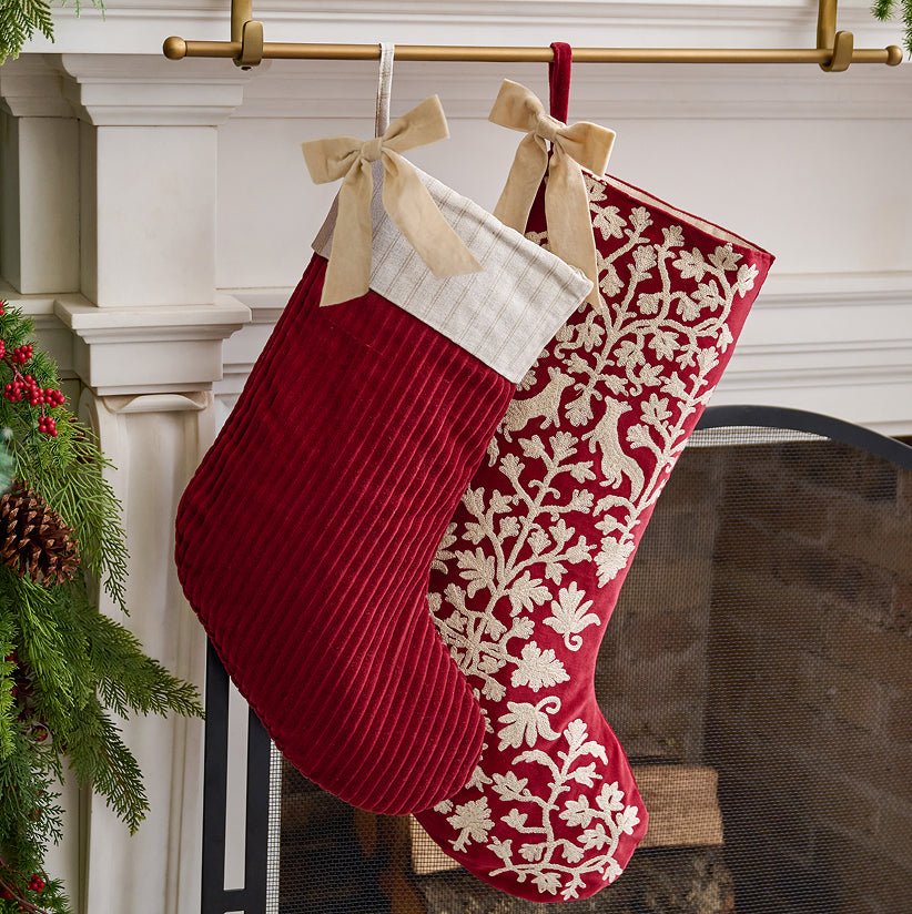 Red Christmas stocking with white floral pattern hanging on a fireplace mantle.