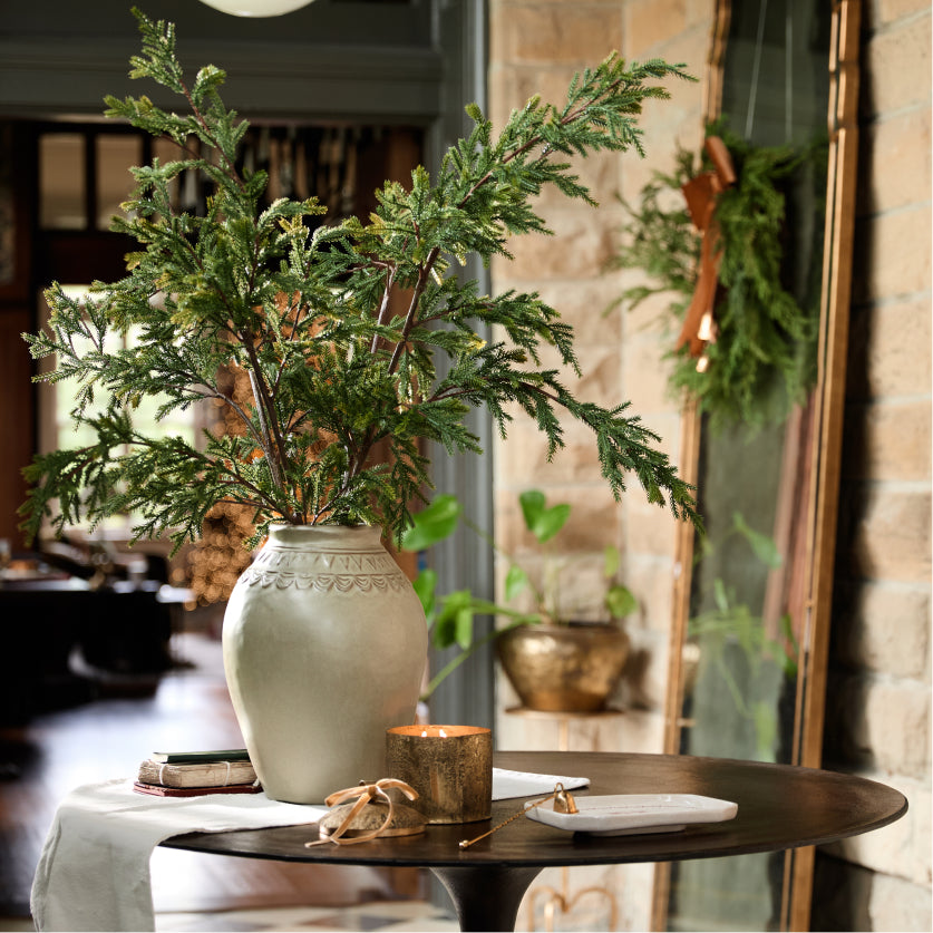 Decorative table setting with a vase of greenery, candle, and small plate in a home interior.  Shop Decor. 