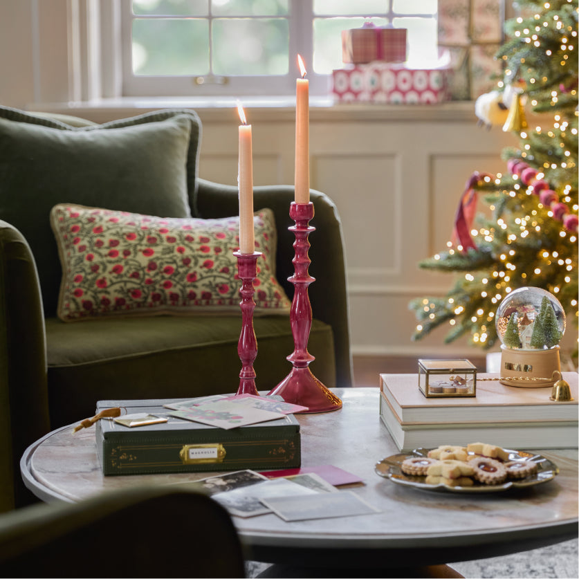 Living room with Christmas decorations, including a tree, candles, and a snow globe.
