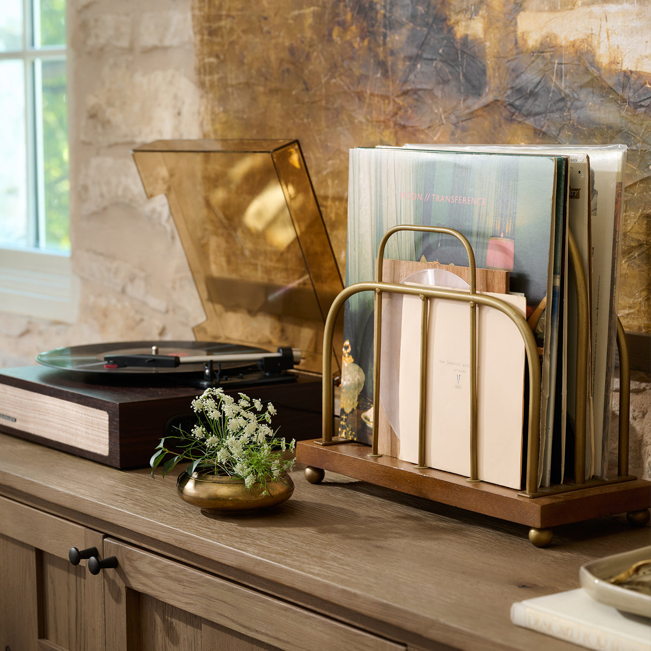Record player with vinyl records on a wooden surface in a cozy room.