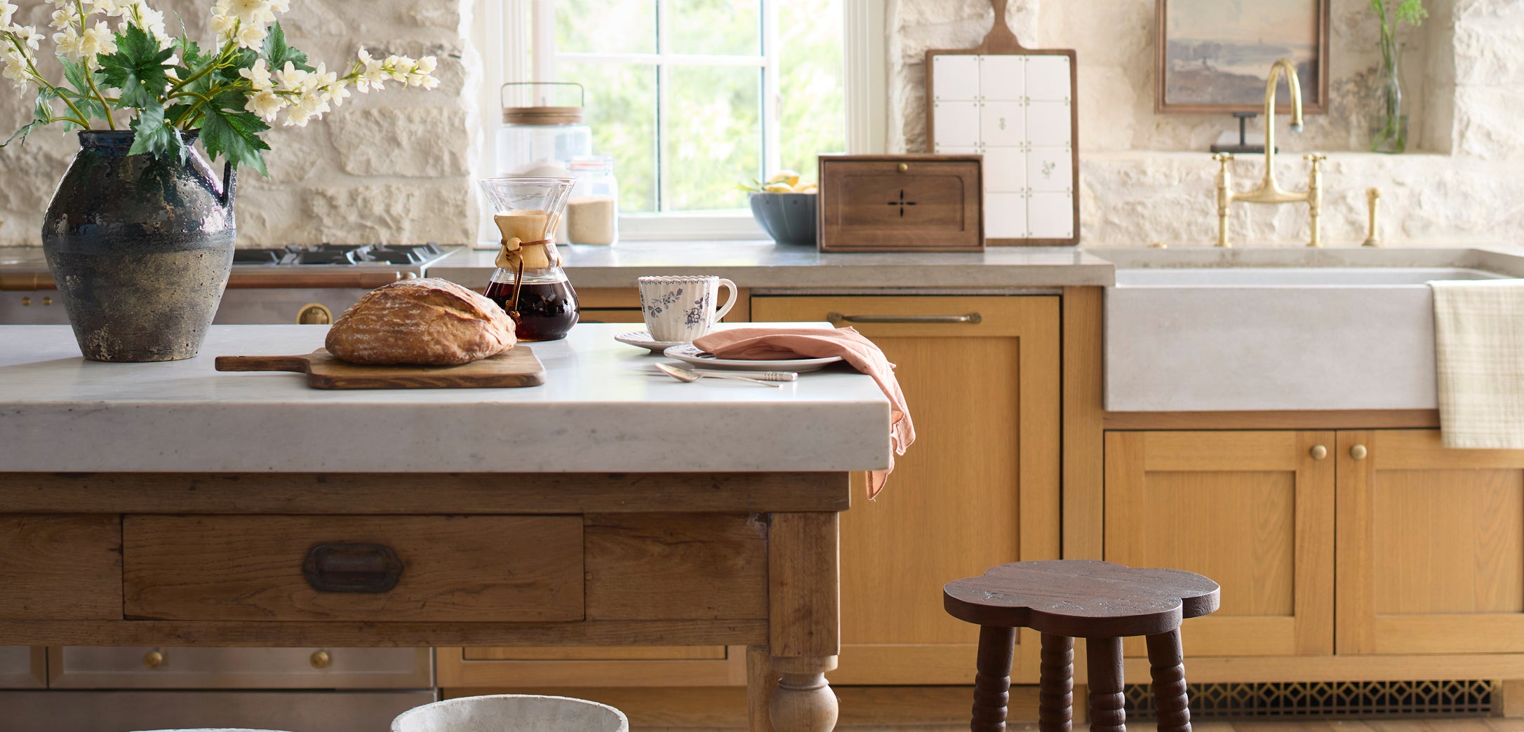 Kitchen with wooden island, bread on a cutting board, and a cup of coffee.