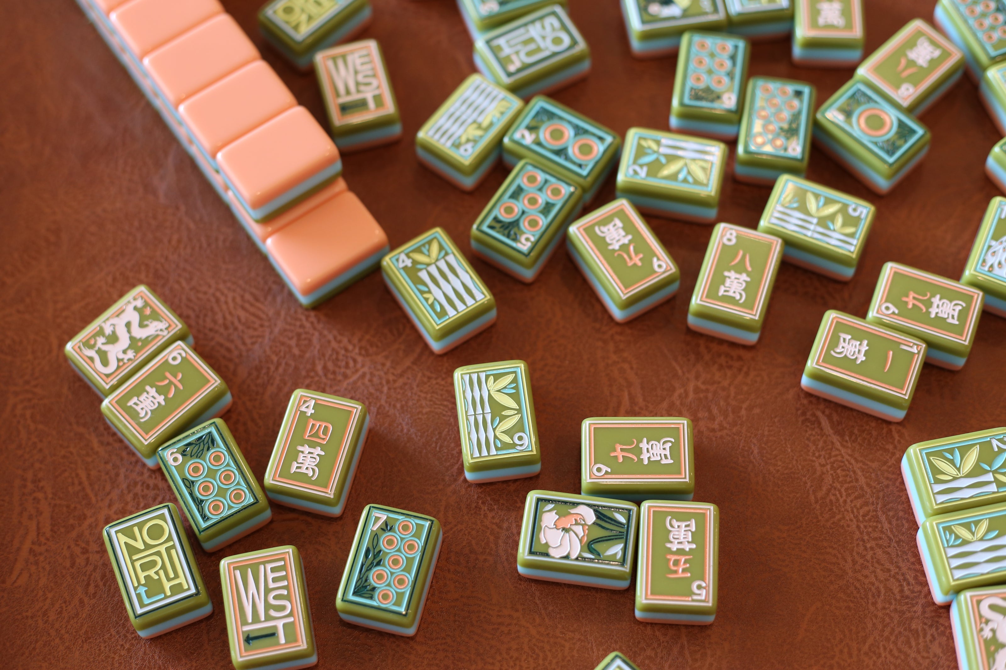Collection of green and orange Mahjong  tiles on a brown surface