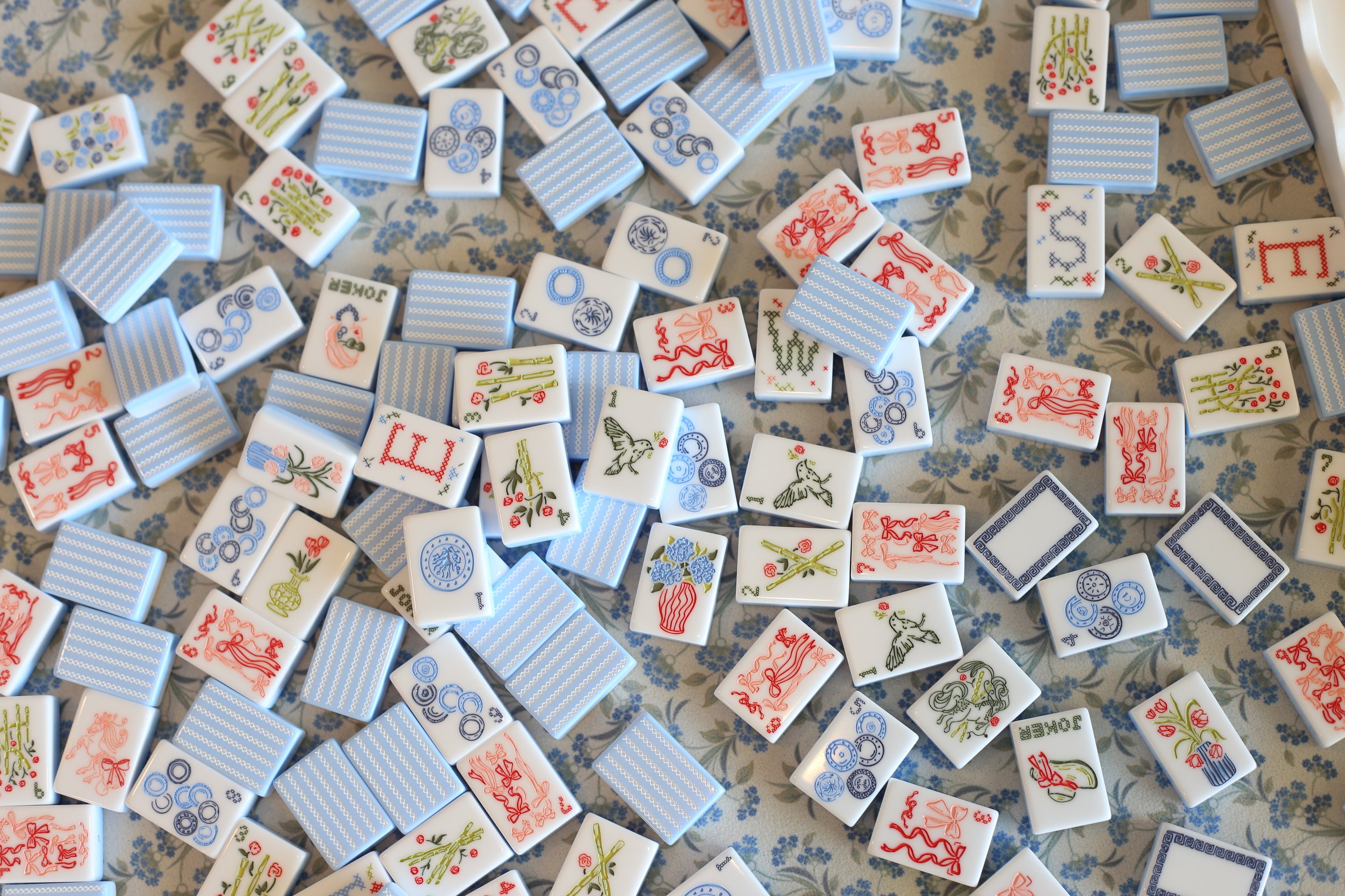 Collection of Mahjong decorative tiles with various patterns on a floral fabric background