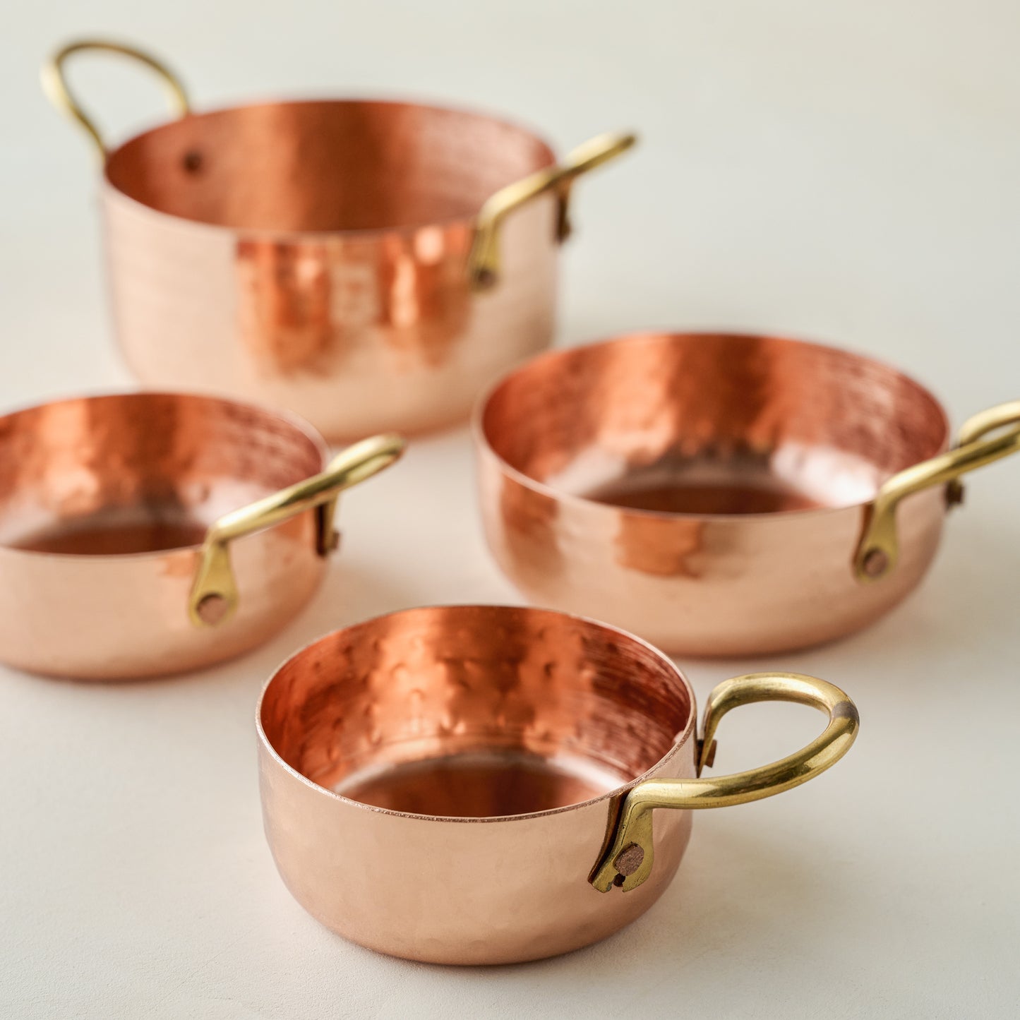 Hammered Copper & Gold Measuring Cups laid out against a white background