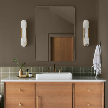 Mosswood paint featured in bathroom walls with marble sconces and light wood cabinetry and white sink