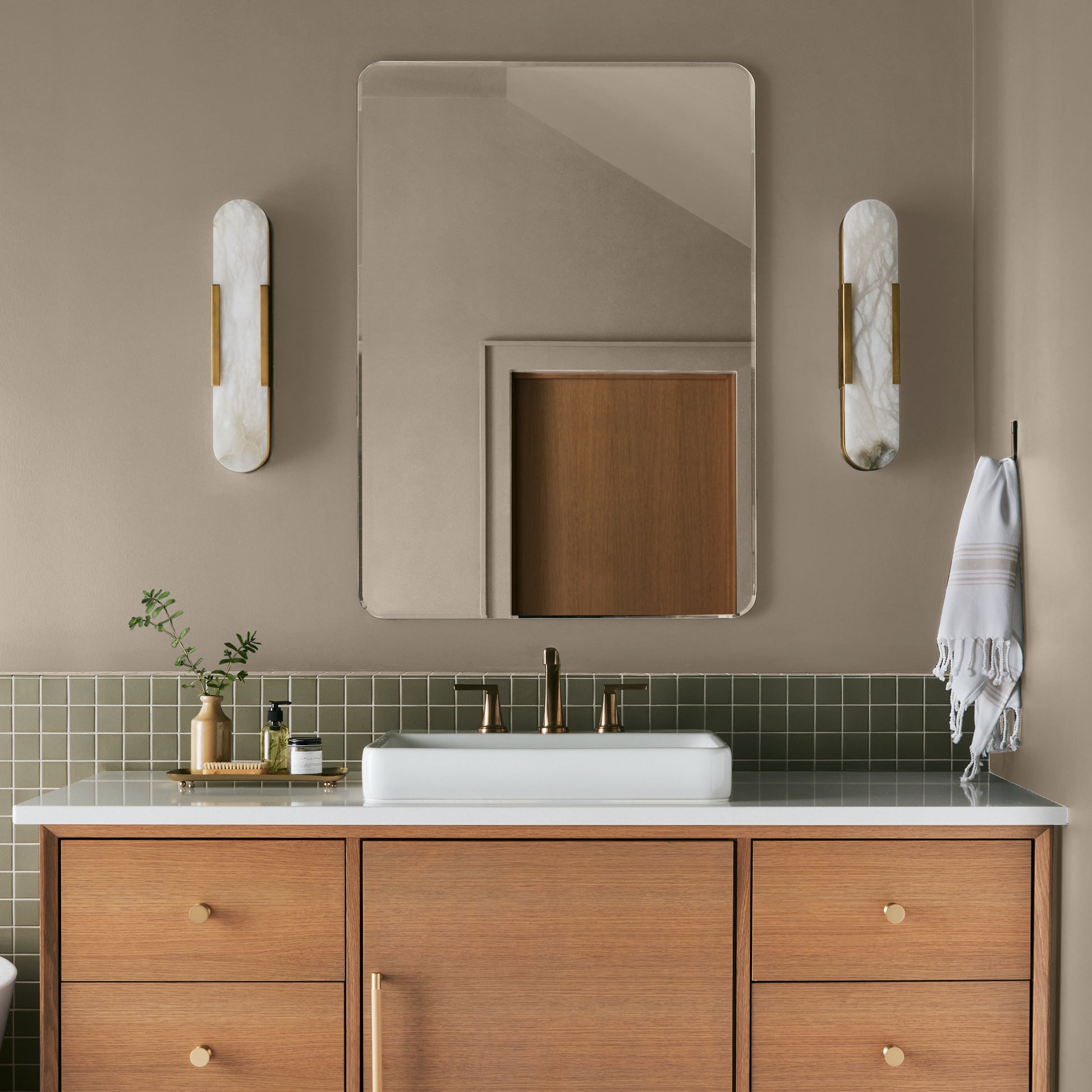 Quaint Cottage paint featured in bathroom walls with marble sconces and light wood cabinetry and white sink