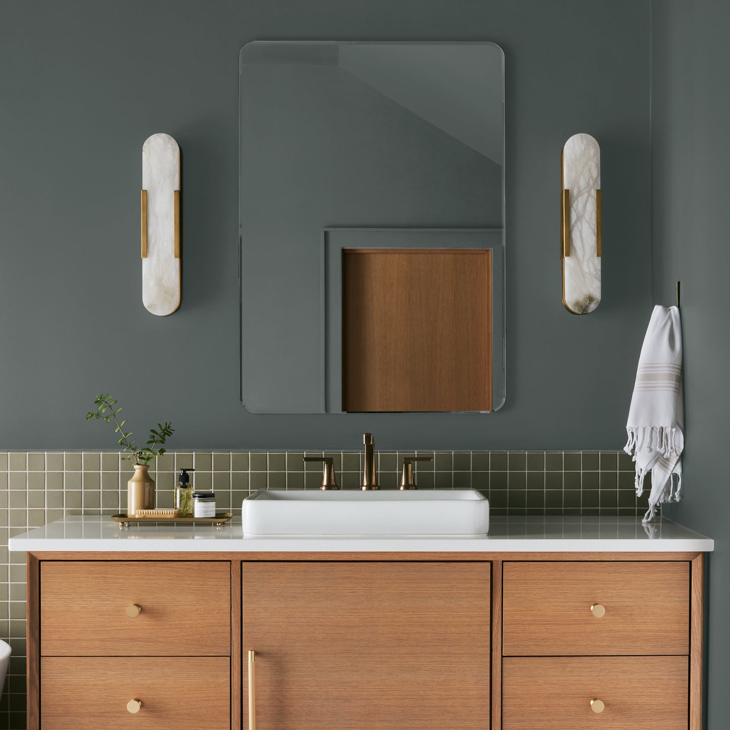 Ridge Rock paint featured in bathroom walls with marble sconces and light wood cabinetry and white sink