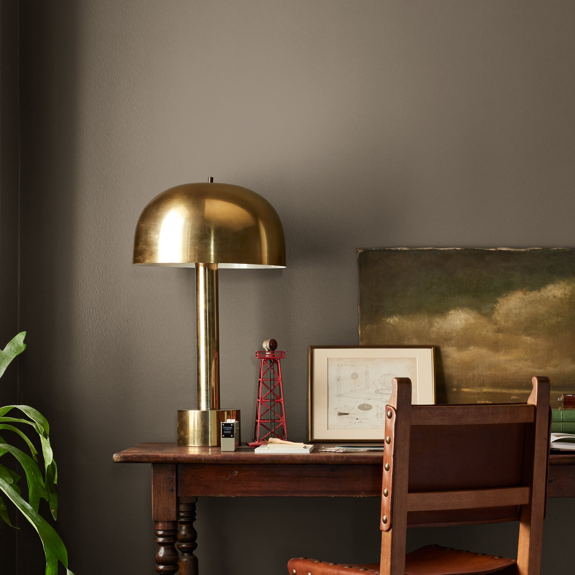 Mosswood paint featured in office area wall with brass lamp, wood table and desk chair, pictures