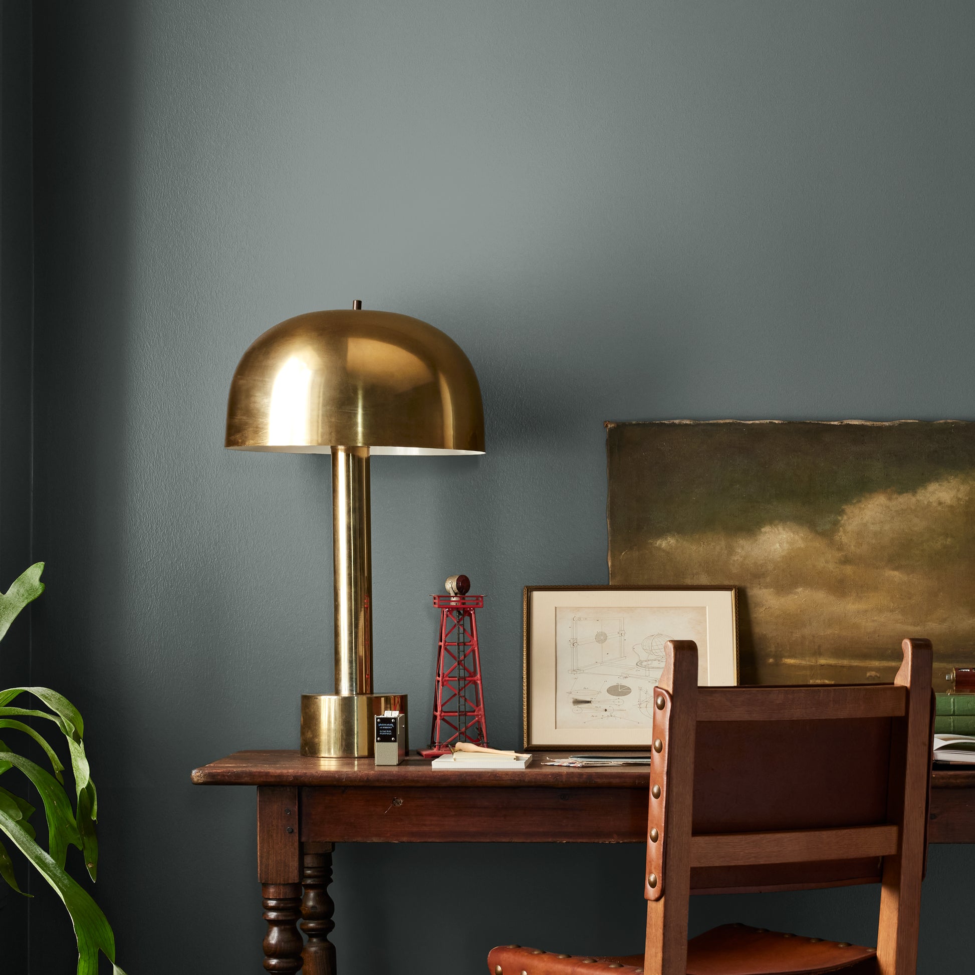 Ridge Rock paint featured in office area wall with brass lamp, wood table and desk chair, pictures