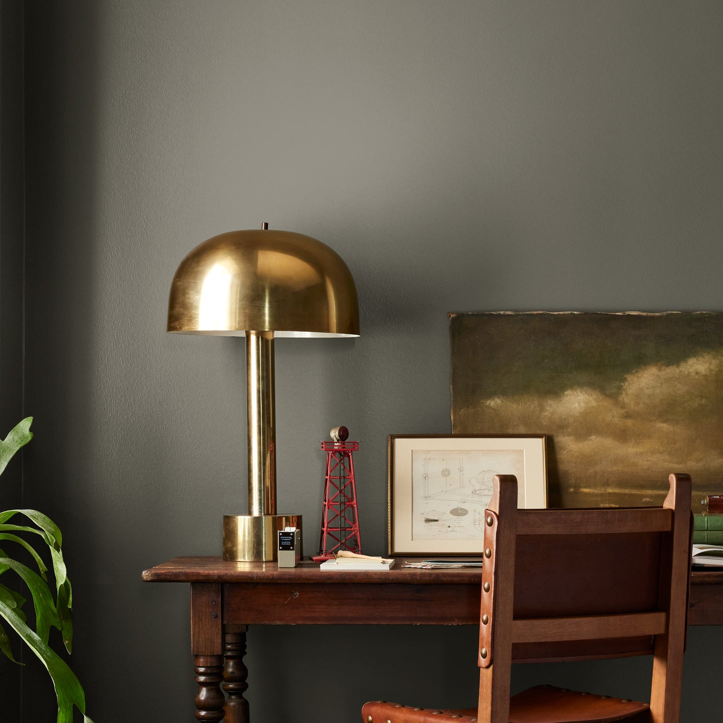 Trailhead paint featured in office area wall with brass lamp, wood table and desk chair, pictures